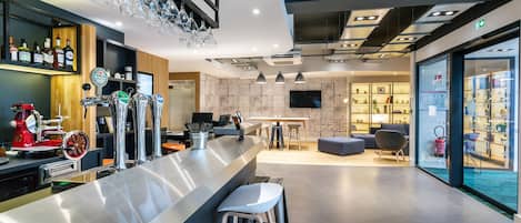 A modern bar area with a stainless steel counter, multiple beer taps, and a seating arrangement with stools.