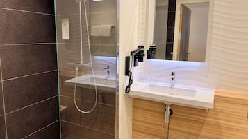 A modern bathroom with a glass-enclosed shower, a vanity with a mirror, and a sink.