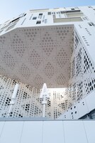 Un edificio moderno con una fachada geométrica que presenta numerosos círculos recortados.