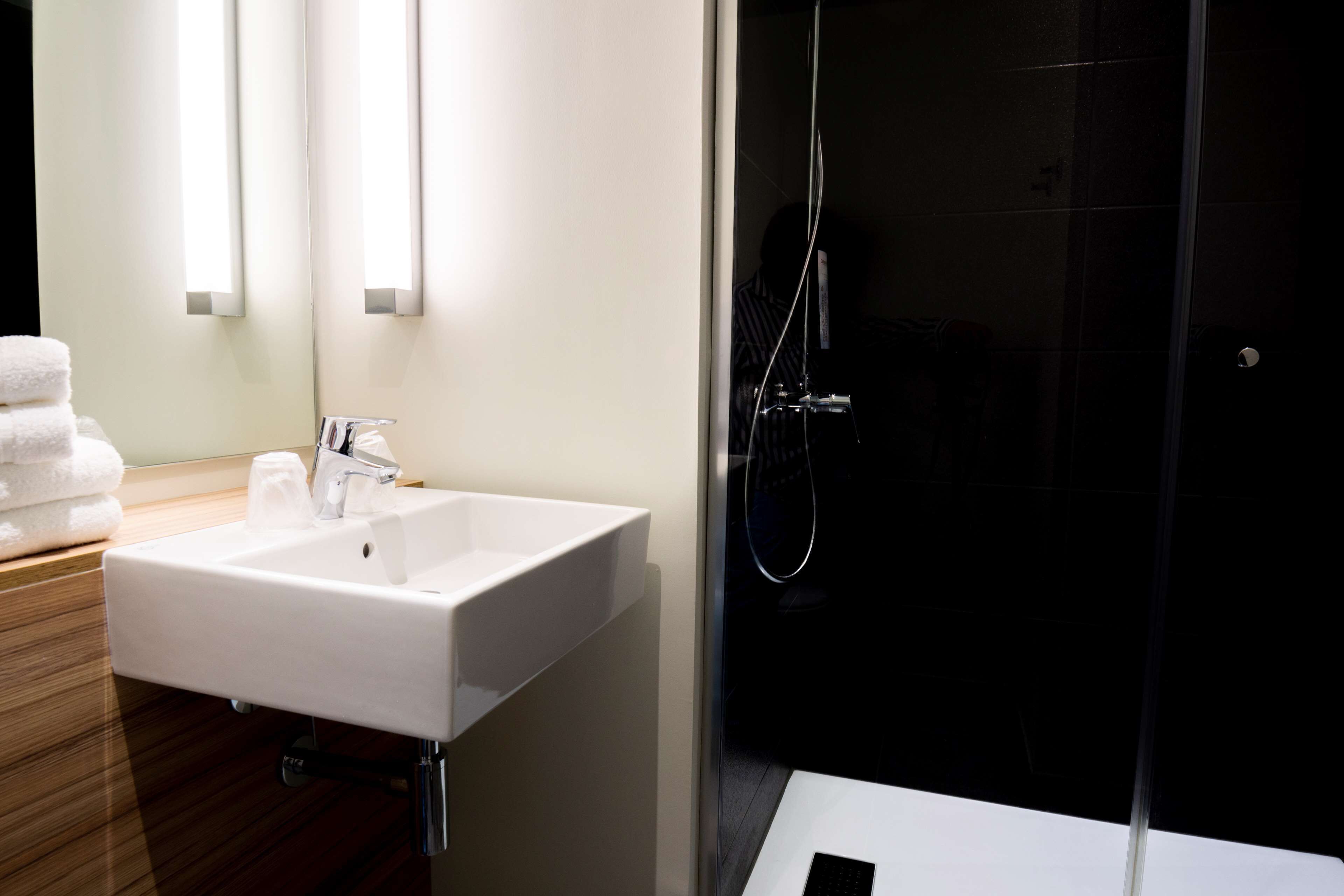 Une salle de bain moderne avec un lavabo blanc, un miroir et une douche à parois de verre.