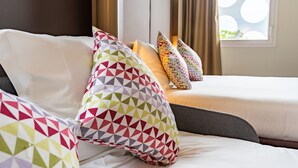 A hotel room with a bed, multiple pillows, a window with a view, and a headboard. - Campanile PRIME - Montpellier Centre St Roch (Montpellier)