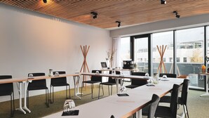 A conference room with a long table, black chairs, and a large window with a city view. - Campanile PRIME - Montpellier Centre St Roch (Montpellier)