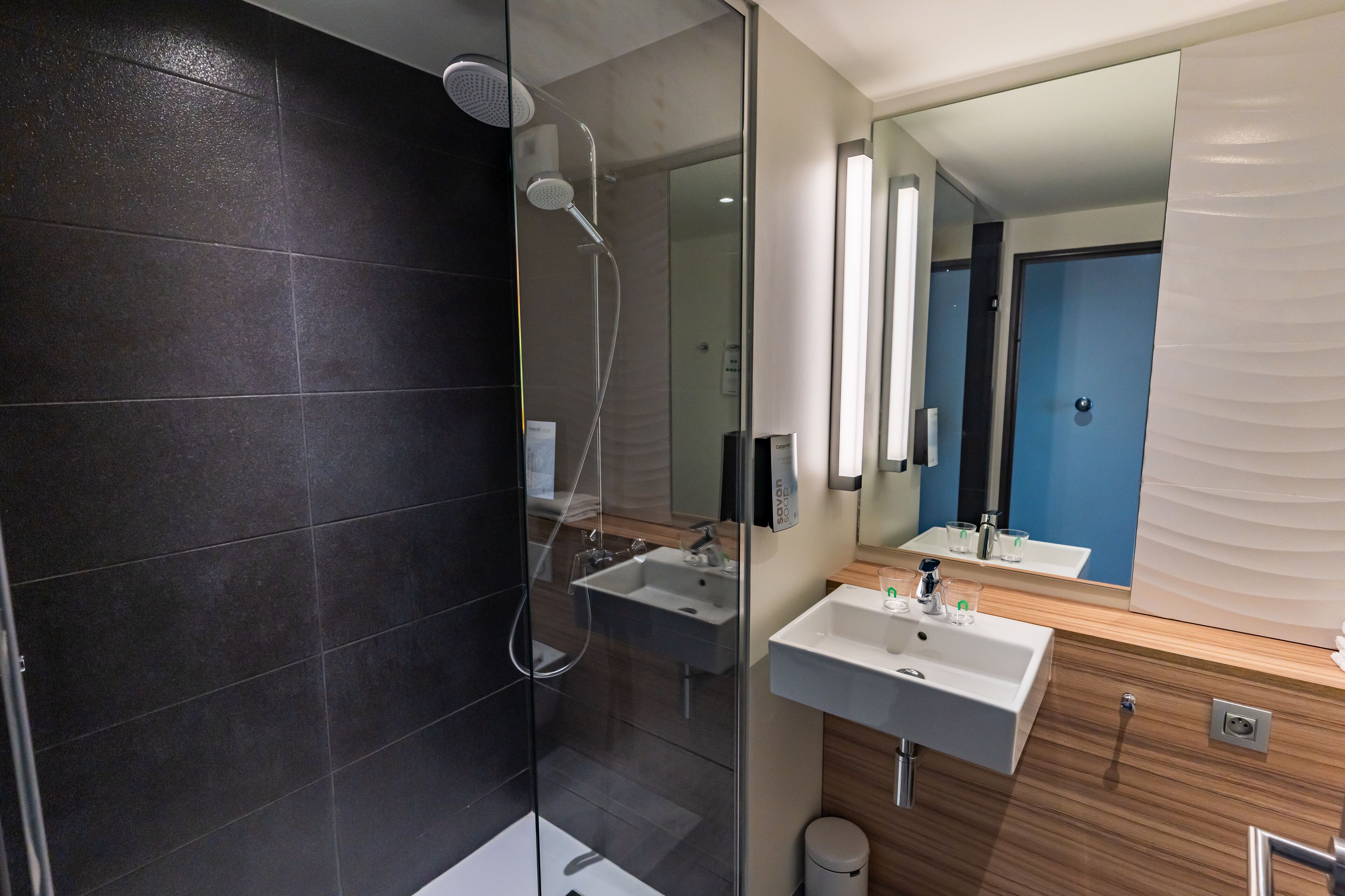 Une salle de bain moderne avec une douche à parois de verre, un lavabo et un miroir.