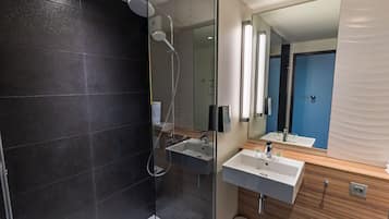Ein modernes Badezimmer mit einer Duschkabine, einem Waschbecken und einem Spiegel.