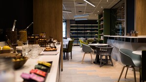 A modern restaurant with a long counter, various seating options, and a visible kitchen area. - Campanile PRIME - Montpellier Centre St Roch (Montpellier)
