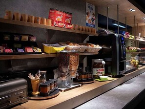 Un comptoir pour le petit-déjeuner avec des condiments, une machine à café et un pot de Nutella.