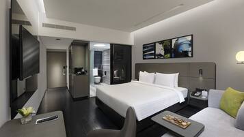 A modern hotel room with a large bed, a flat-screen TV, a desk with a remote control, and a small table with a decorative item.