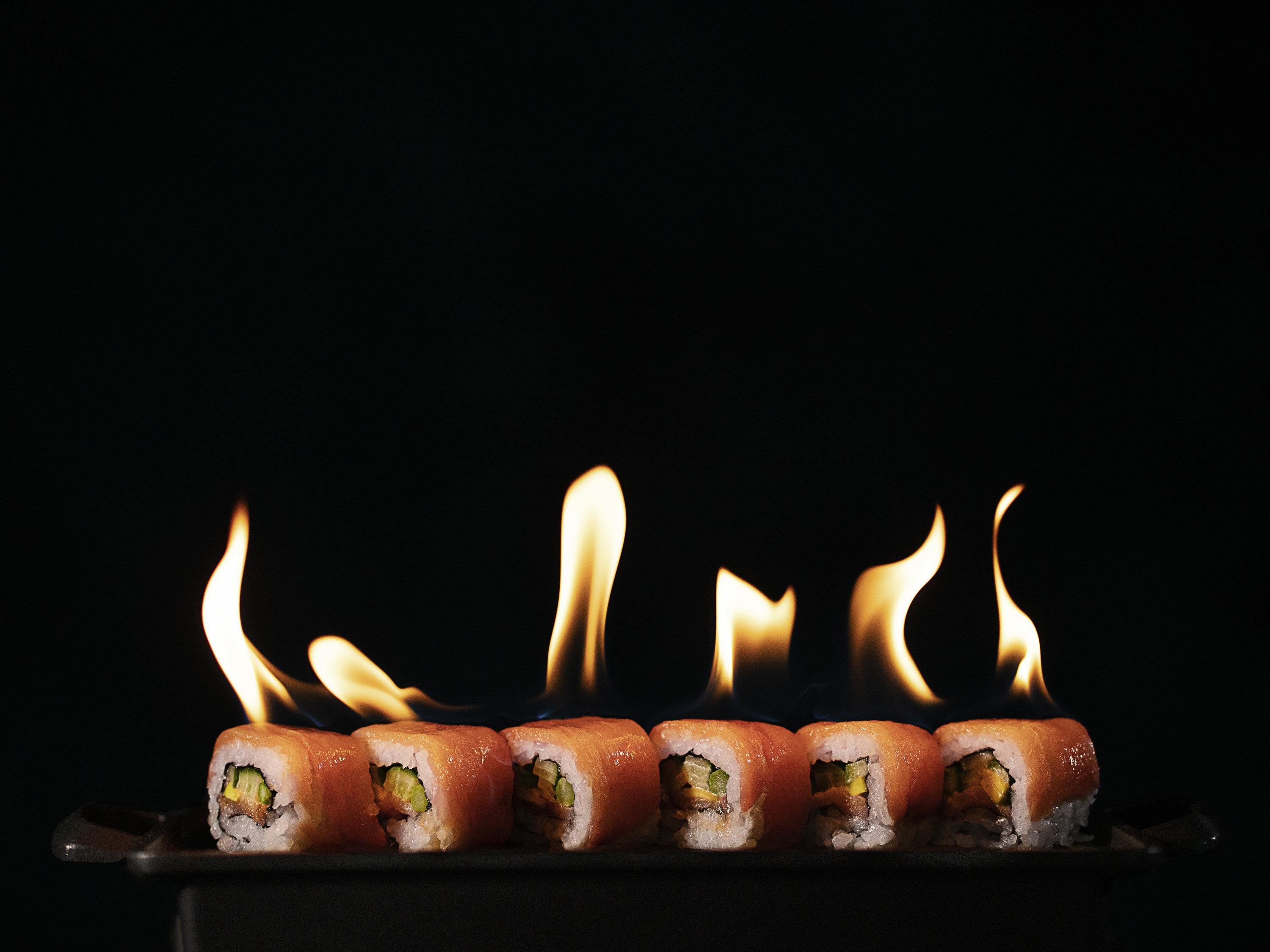 Sushi rolls on a tray with flames.