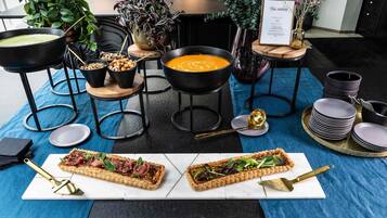 A dining area with a table set for two, featuring a variety of dishes, including a soup and a tart, and a menu sign.