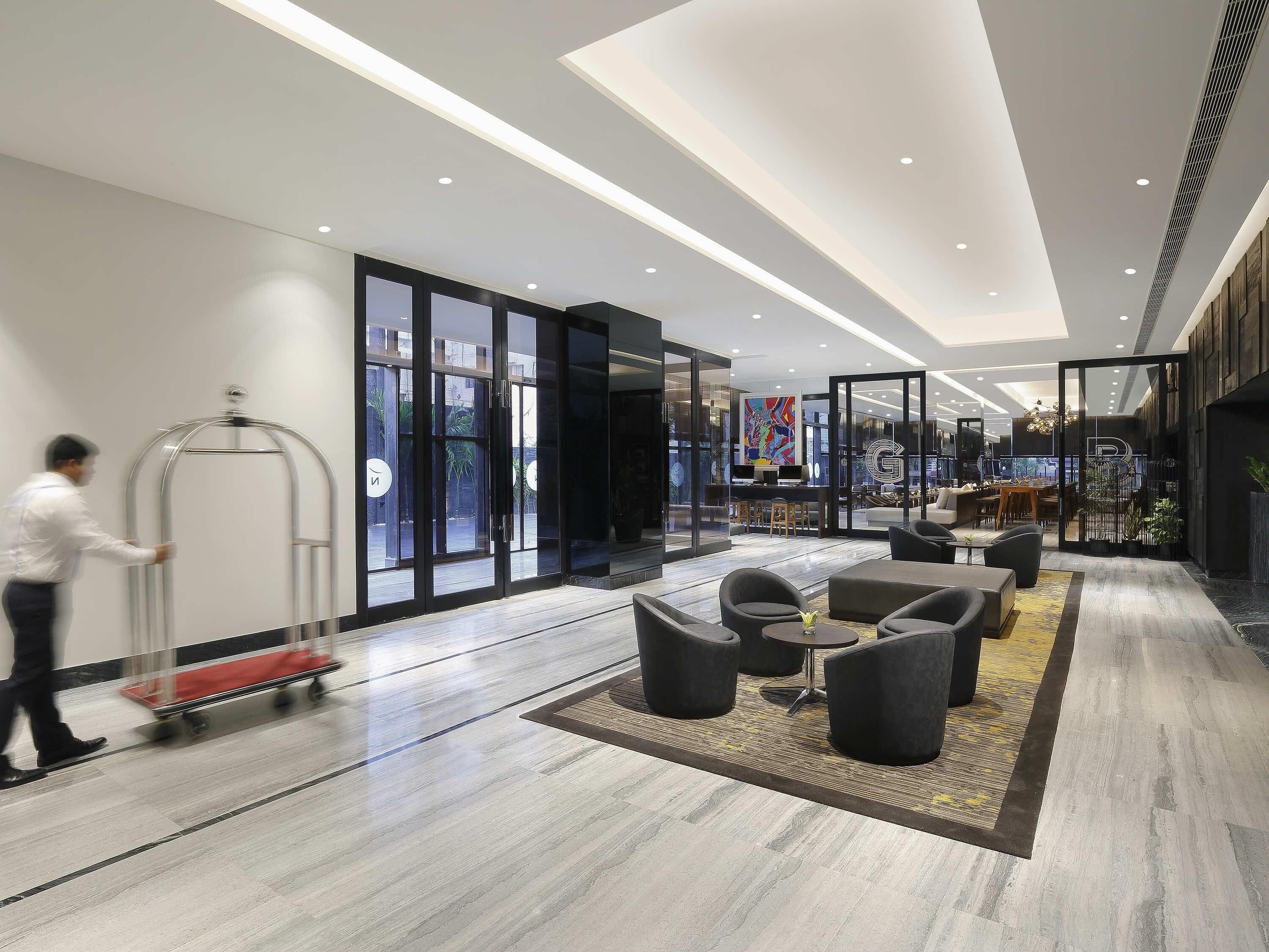 Un hall d’hôtel moderne avec un comptoir d’accueil, un espace salon et de grandes fenêtres.
