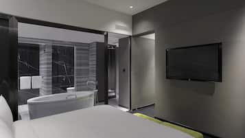Una habitación de hotel moderna con una cama grande, un televisor montado en la pared y un baño con bañera y ducha.