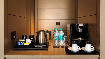 A compact kitchenette with a coffee maker, water bottles, and a kettle.