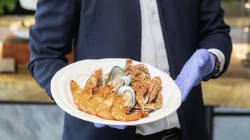 A person holding a plate with seafood, wearing a uniform and gloves.