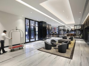 Eine moderne Hotelhalle mit einer Rezeption, einer Sitzecke und großen Fenstern.