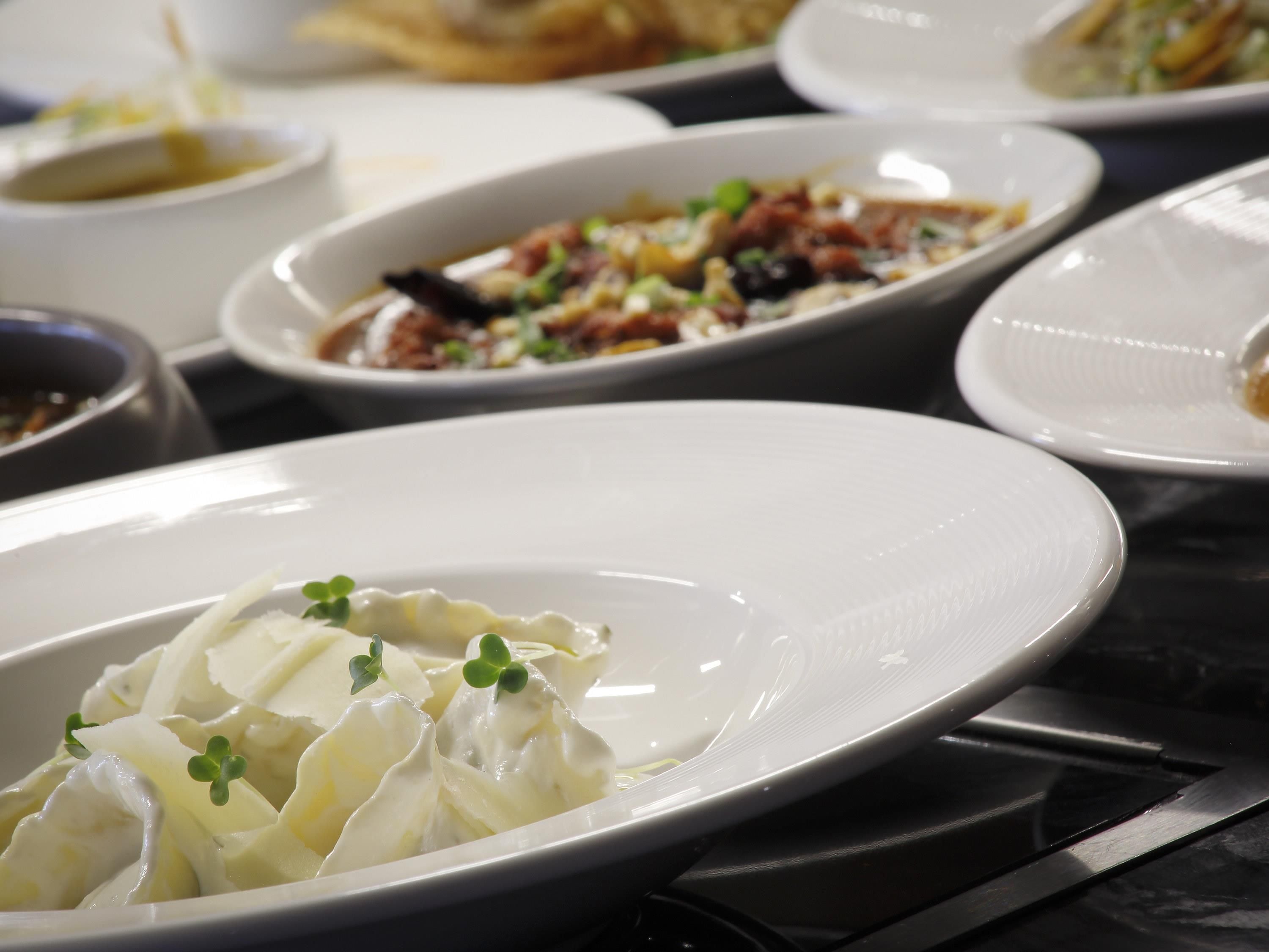 Una mesa de comedor con varios platos, incluyendo un plato de dumplings adornados con vegetales.