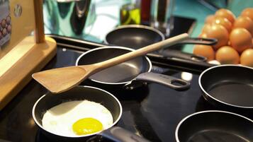 A kitchen with a frying pan on an induction cooktop, a wooden spatula, and a pot.