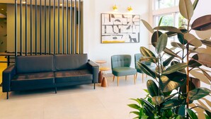 A modern living room with a black sofa, a green armchair, and a large plant. - ibis Styles Goiania Marista (Goiania)