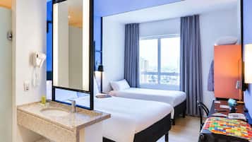 A hotel room with a bed, a desk, a chair, a large window, a mirror, a telephone, and a sink.