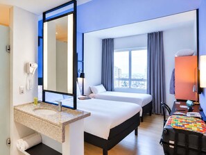 A hotel room with a bed, a desk, a chair, a large window, a mirror, a telephone, and a sink. - ibis Styles Goiania Marista (Goiania)