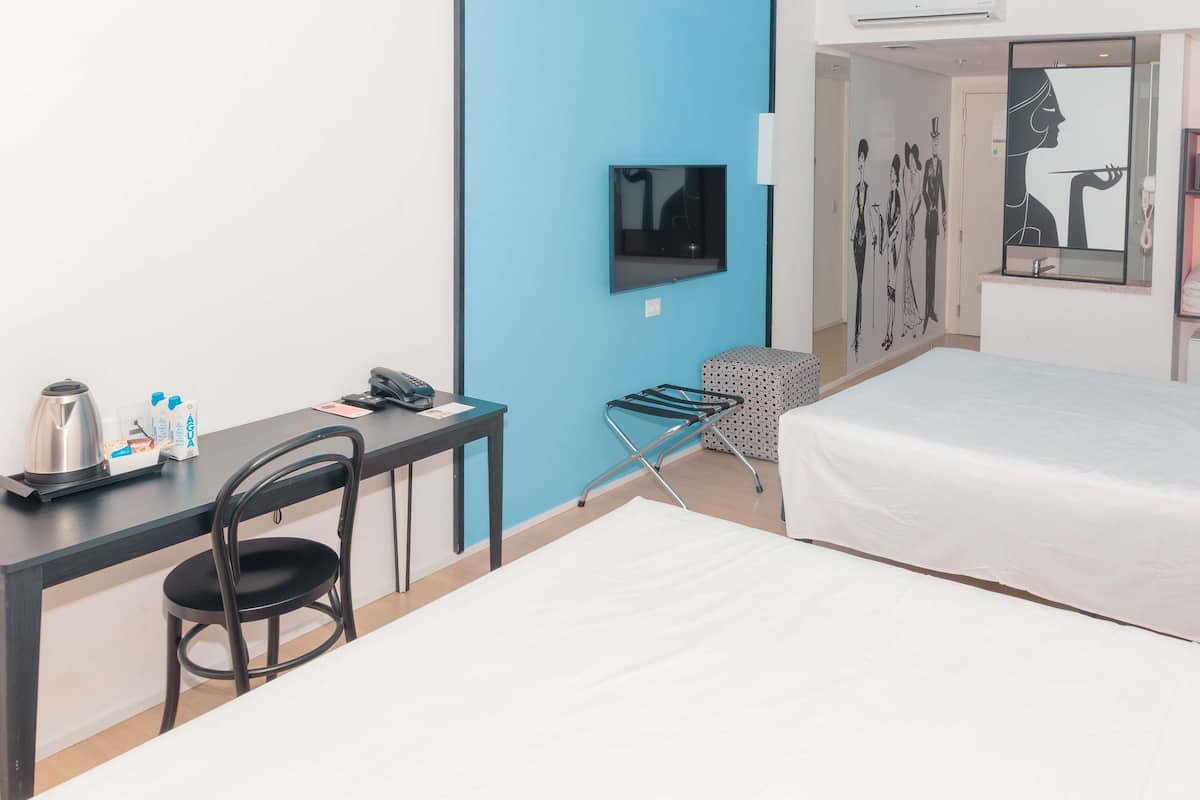 Een hotelkamer met een bureau, stoel, bed en een klein zithoekje.