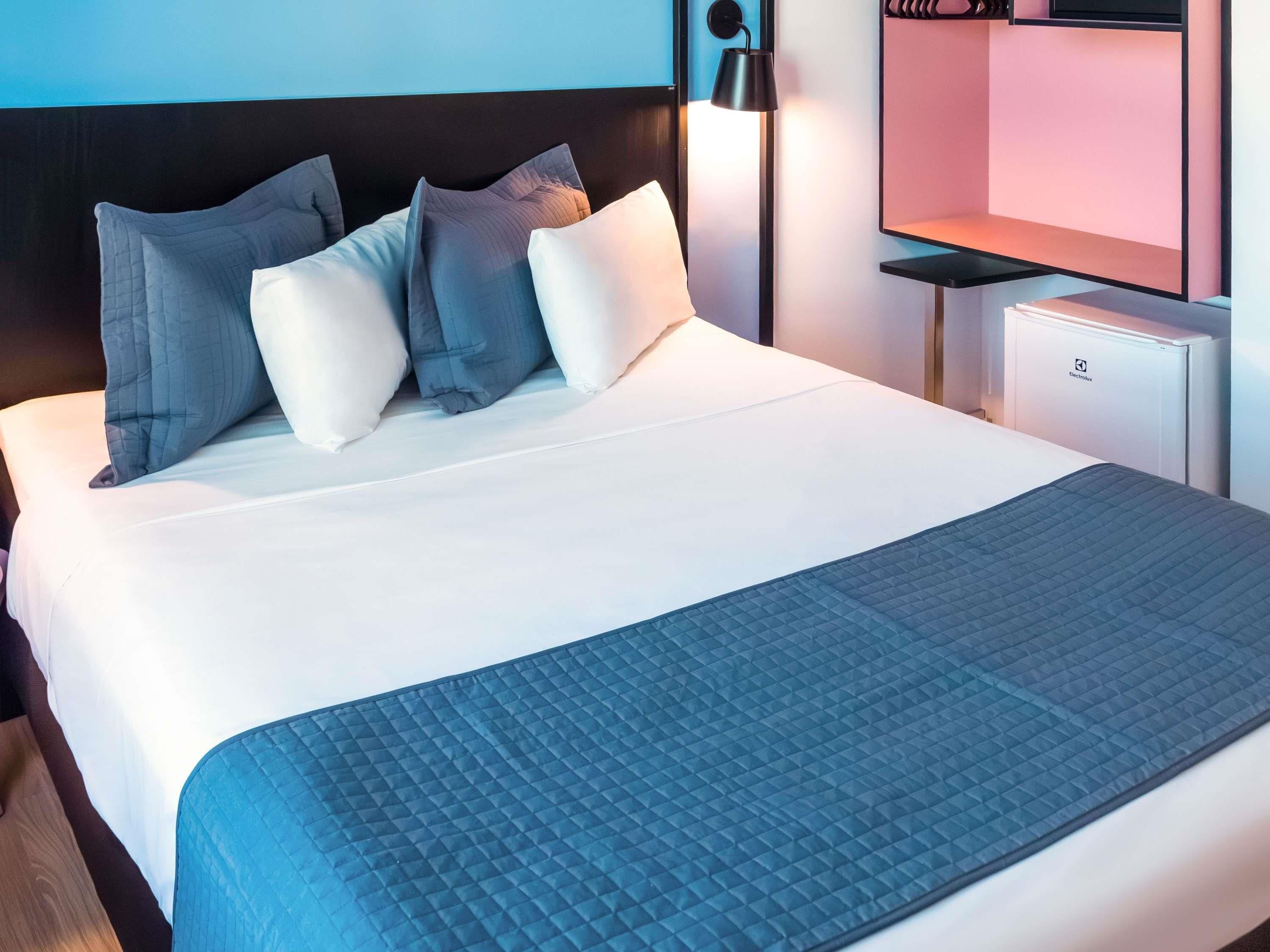 Cama bem arrumada com edredom branco e manta acolchoada azul.