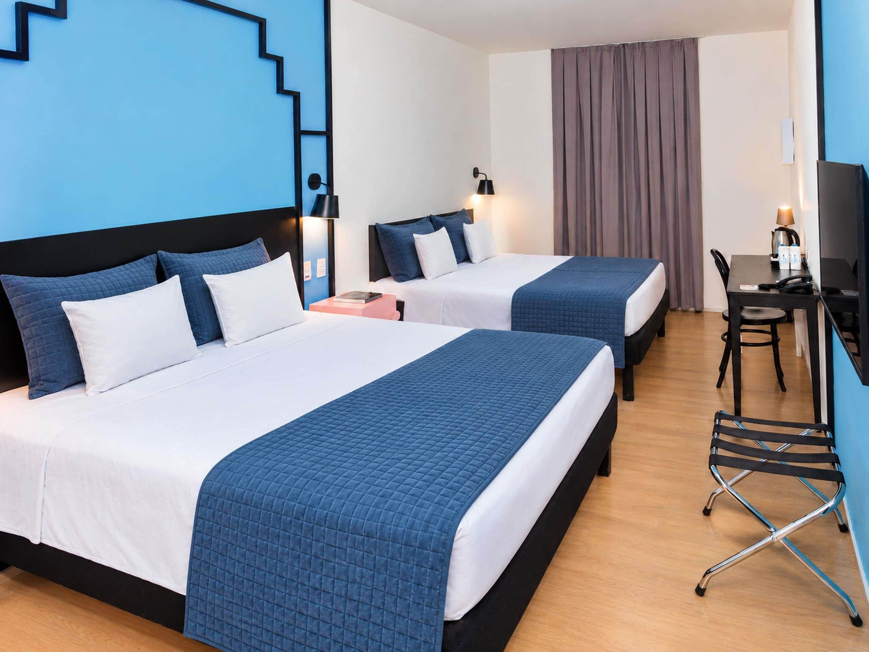 Une chambre d’hôtel avec deux lits, un bureau, une chaise et un téléviseur.