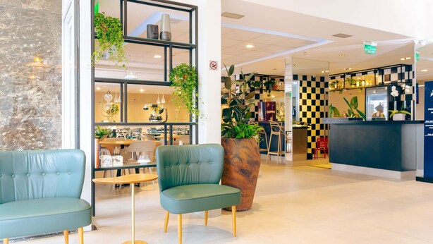 A modern interior with seating areas, a reception desk, and a checkered wall design. - ibis Styles Goiania Marista (Goiania)