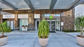 A modern building entrance with a glass canopy, potted plants, and signs for 'Art Deco Marista' and 'Colonia Marista' restaurants. - ibis Styles Goiania Marista (Goiania)