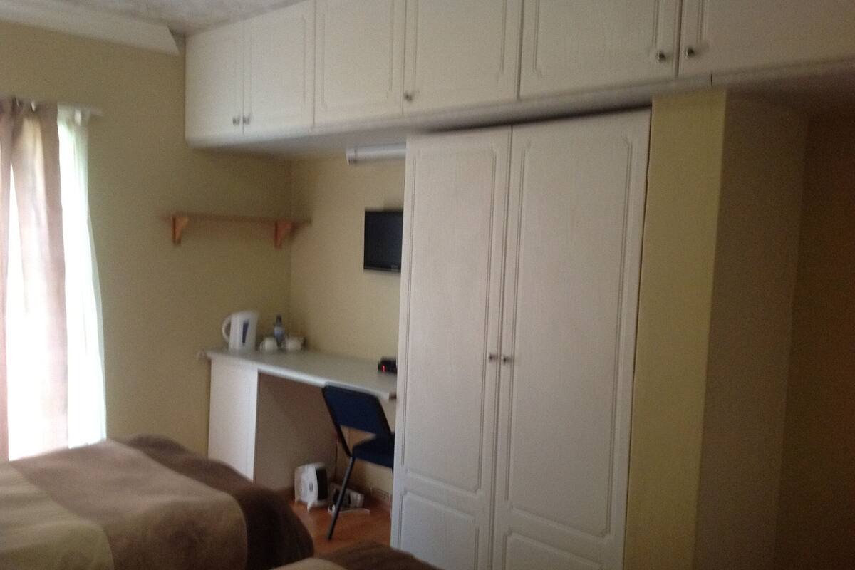 A room with two beds, a desk, a chair, and a wardrobe.
