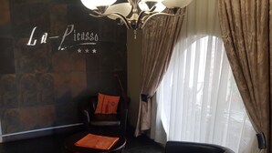 A lobby with a black leather chair, a smaller armchair, a small table, and a wall with 'La Picasso' signage. - La Picasso Guesthouse (Ermelo)