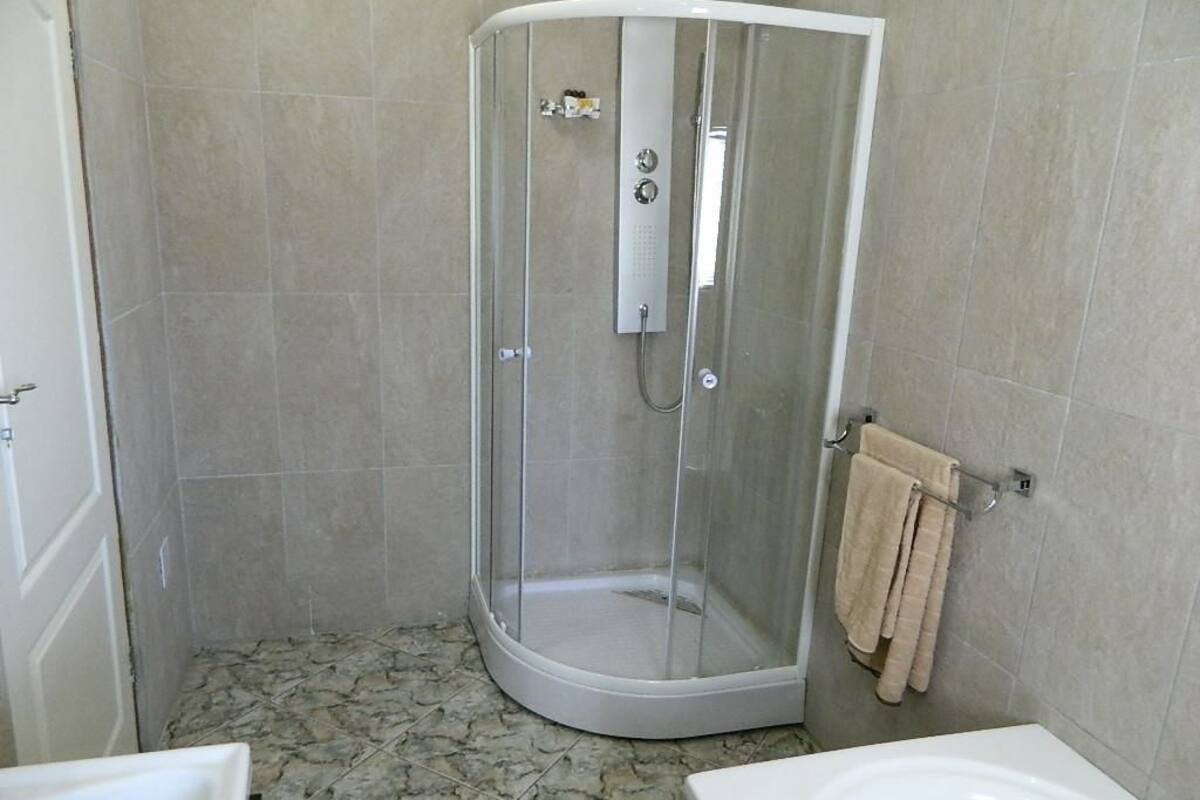 A shower with a glass door, a towel rack, and a tiled floor.