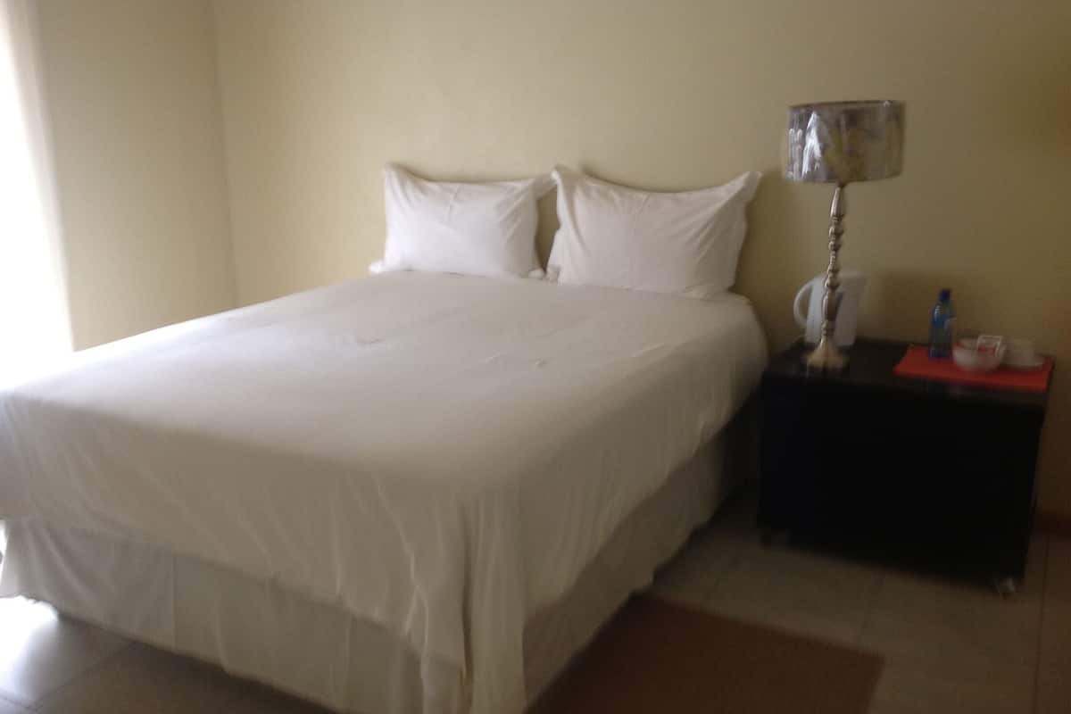 A neatly made bed with white linens in a hotel room.