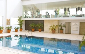 An indoor swimming pool with a clear view of the upper floor, potted plants, and exercise equipment. - St Giles Makati (Makati)