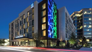 A modern hotel with a prominent digital display on the facade, large windows, and a well-lit entrance. - AC Hotel by Marriott Tampa Airport (Tampa)