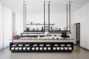 A modern kitchen with a central island, black shelving, and a variety of kitchenware. - AC Hotel by Marriott Tampa Airport (Tampa)