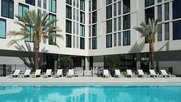 Una piscina al aire libre, sillones reclinables de piscina