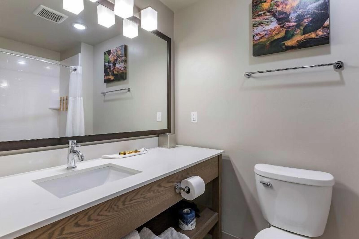 A bathroom with a white sink, a mirror, a toilet, and a towel rack.
