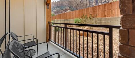A balcony with a view of a wooden fence and mountains.