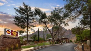 L’entrée d’un hôtel, avec une enseigne indiquant « Best Western Plus Zion Canyon », et une vue sur des montagnes en arrière-plan.