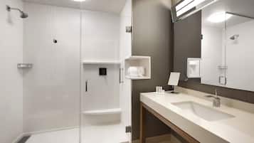 Un baño moderno con cabina de ducha, un espejo grande y un lavabo con tocador.