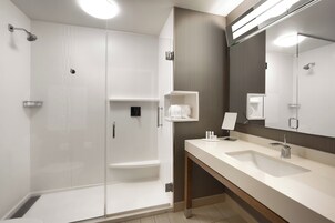 Un baño moderno con cabina de ducha, un espejo grande y un lavabo con tocador.