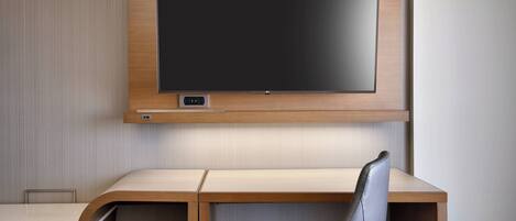 Ein modernes Hotelzimmer mit einem Holzbüro, einem Ledersessel und einem an der Wand befestigten Flachbildfernseher.