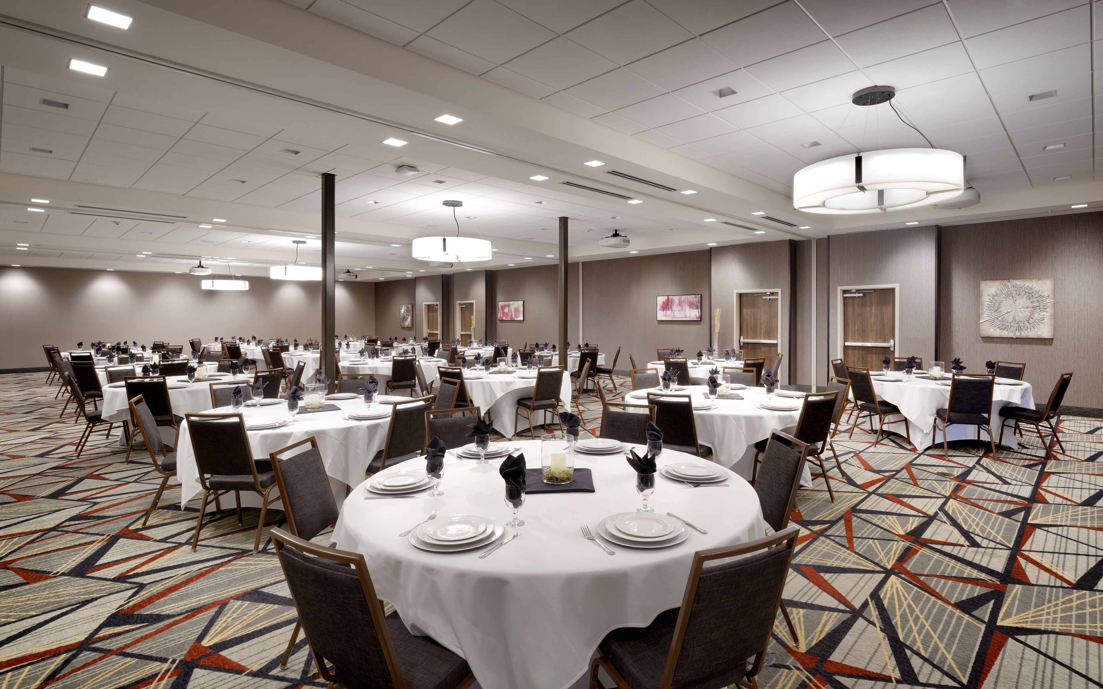 A large conference room with round tables, chairs, and a patterned carpet.