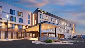 Um hotel Courtyard Marriott com design moderno, apresentando uma entrada coberta e vários andares.