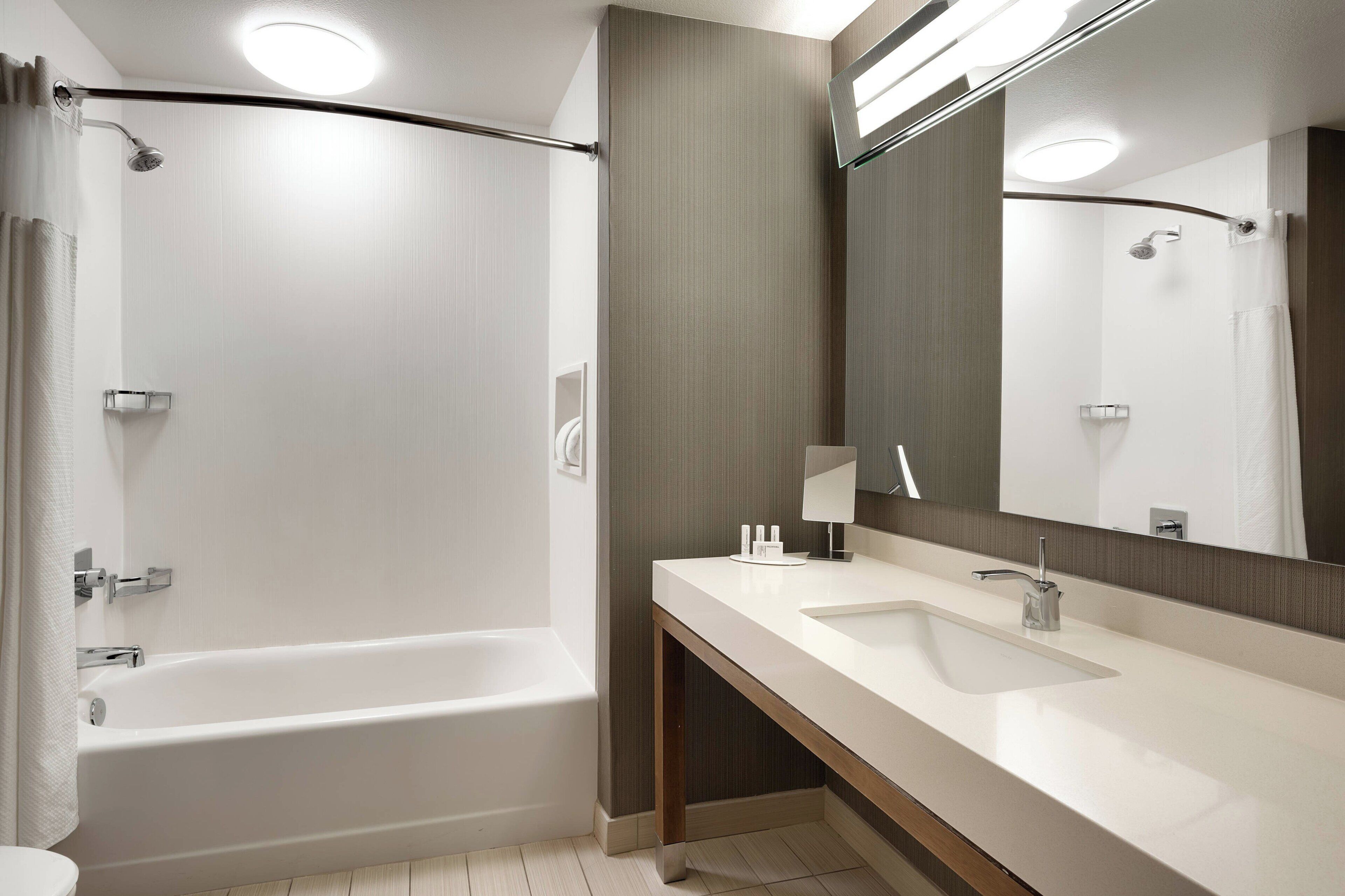 A modern bathroom with a bathtub, a sink, and a mirror.