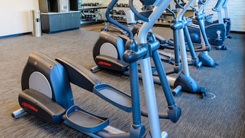 A gym with multiple treadmills and dumbbells.