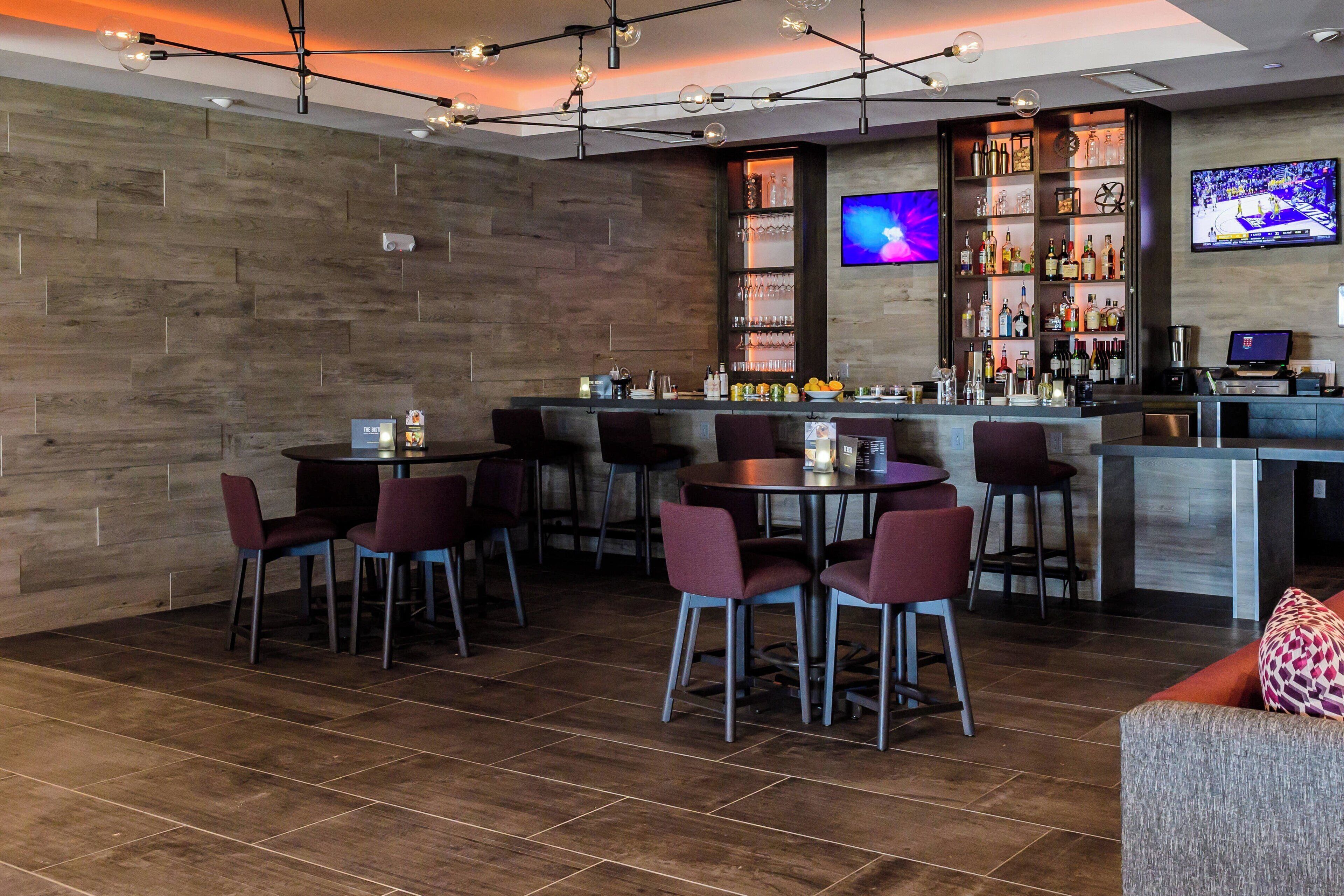 A bar area with multiple seating options, a bar counter, and a television screen.