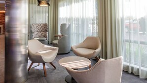 Een moderne lobby met drie stoelen, een ronde tafel en een hoge zuil.