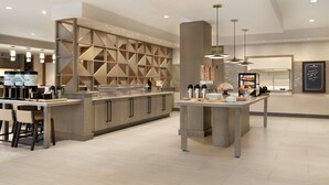 A modern kitchen with a central island, built-in appliances, and a geometric wall design. - Hilton Garden Inn Newtown Square Radnor (Newtown Square)