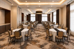 Un salón de conferencias con mesas redondas y sillas, suelo alfombrado y una gran lámpara de araña.